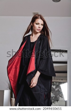 Cropped image of young European lady wearing dramatic outfit composed of long black dress and a loose robe. Catalog shooting for online store or magazine. Studio editorial photography, copy space
