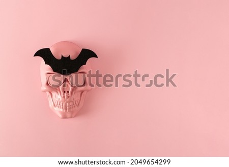 Creative idea made of pink skull mask with sunglasses and black bat. Minimal scary pink Halloween or day of the dead concept. Copy space. Flat lay.