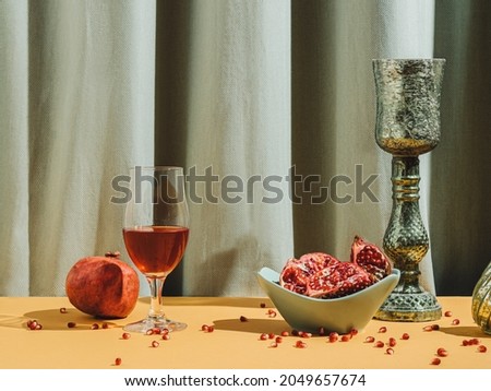 Retro styled still life arrangement with pomegranate fruit and juice with green curtain. Autumn colors. Seasonal background. Retro aesthetic.