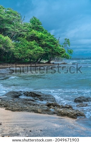 Beautiful coastline of Pacific COsta Rica. Rocks on the foreground and tropical vegetation on the background. Before the sunset.
