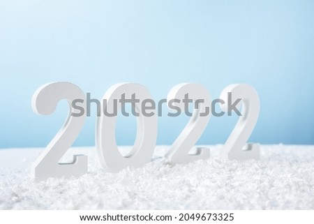 Happy New Year 2022. Decorative white number 2022 with snow isolated on blue background. Greeting christmas card with copy space.