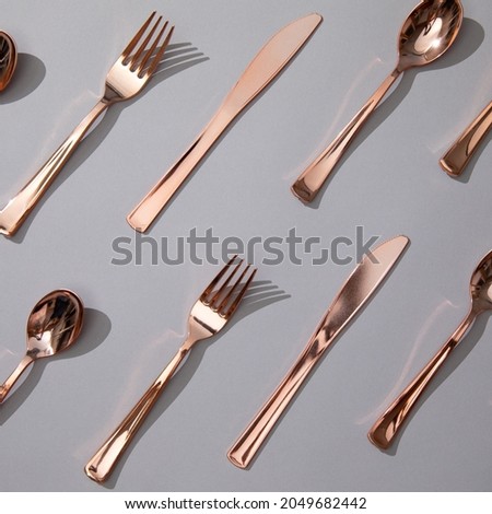 Rose Gold Dinnerware Cutlery Utensils, Forks Knives, Spoons on Gray Background Royalty-Free Stock Photo #2049682442