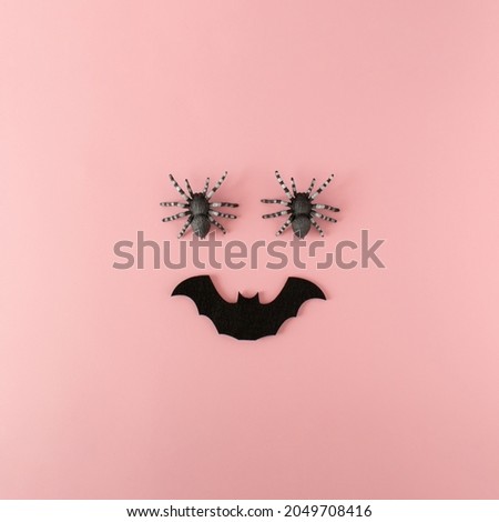 Minimalist ic happy Halloween face made of spiders and bat on pink background. Creative fun Halloween concept. Flat lay.