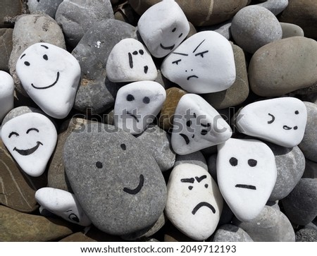 Emotion management concept, stones with painted faces symbolize different emotions. Learning to manage emotions. Funny, sad, surprised, angry, different faces.
