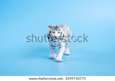 the tiger, symbol of 2022 year. plastic white toy figure tiger on a blue background