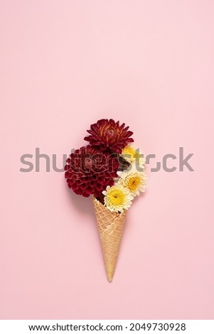 Waffle ice cream cone with  flowers on pink background. Top view .Copy space for text.
