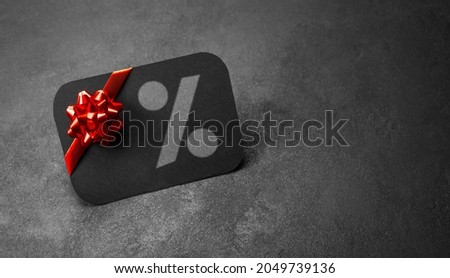 Black discount card with a red bow on a gray background.