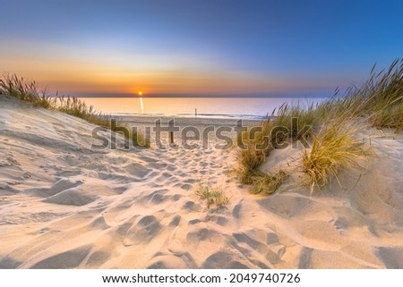 Inviting Sunset View over ocean from dune over North Sea and Canal in Ouddorp, Zeeland Province, the Netherlands. Outdoor scene of coast in nature of Europe. Royalty-Free Stock Photo #2049740726