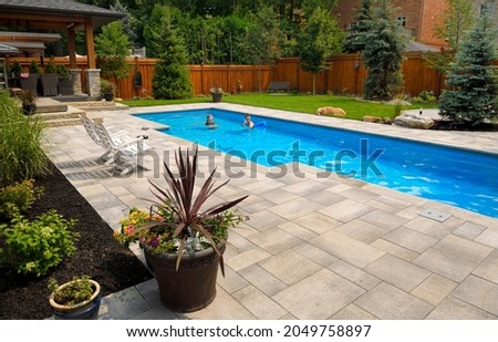 Mother and daughter swimming in new back yard pool with dog a patio of pavers and green lawn and gardens Royalty-Free Stock Photo #2049758897
