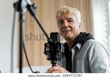 Portrait of a radio host transmitting news. Speaks into the microphone in the studio. Live podcast recording for the show. The presenter on the radio communicates with listeners. Works on a laptop.