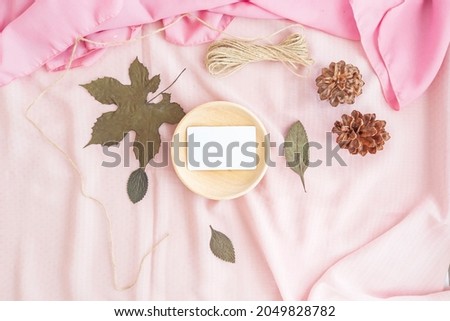 The composition displays the product. minimalistic background of business card decorated with wood, cloth, dried leaves and pine flowers. minimalist composition featuring products
