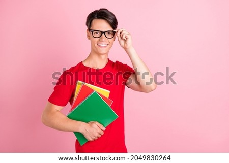 Photo of young guy happy positive smile wear glasses hold notebook study education isolated over pink color background