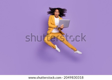 Photo of shocked pretty woman dressed yellow suit spectacles typing modern device jumping isolated violet color background