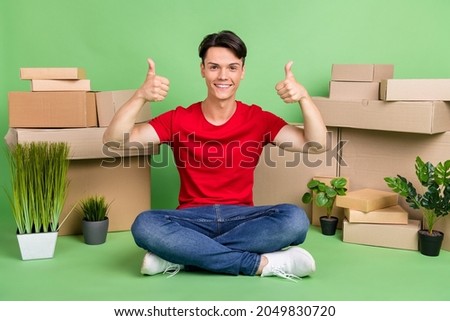 Full size photo of young guy happy smile box buy new accommodation show thumb-up fine great isolated over green color background