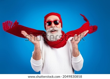 Photo of funny shocked mature man dressed white pullover red glasses headwear rising arms smiling isolated blue color background