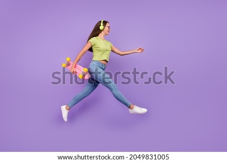 Full length body size view of nice cheerful girl jumping listening single hit going with skate isolated over purple violet color background