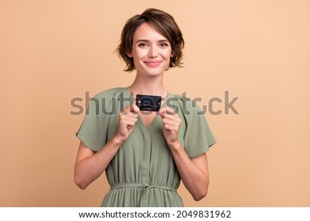 Photo of cheerful pretty lady presenting debit card investment income wear green dress isolated beige color background