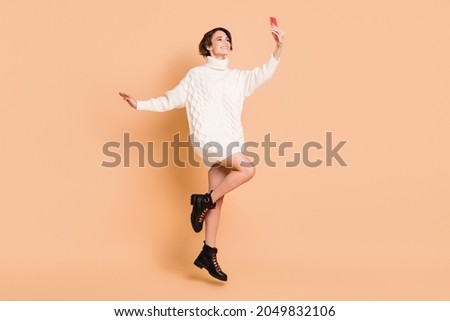 Full length photo of brunette bob haired woman jump up hold phone take selfie isolated on beige color background