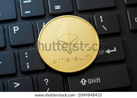 Closeup photo of gold coin with ethereum symbol on black keyboard background