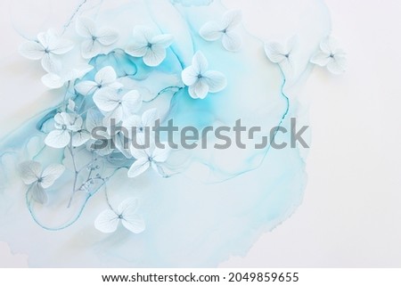 Creative image of pastel blue Hydrangea flowers on artistic ink background. Top view with copy space