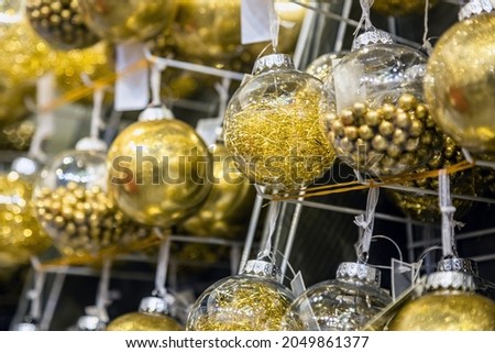 Christmas ball hangs on a shelf in the store among other Christmas toys. Focus in ball