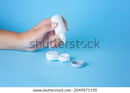 Contact lens on finger and bottle of solution close-up. Selective focus on lens. Copy space. High quality photo