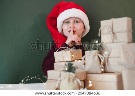 Child's showing finger points quietlyon the background of Christmas gifts. Plastic free sustainable lifestyle. High quality photo