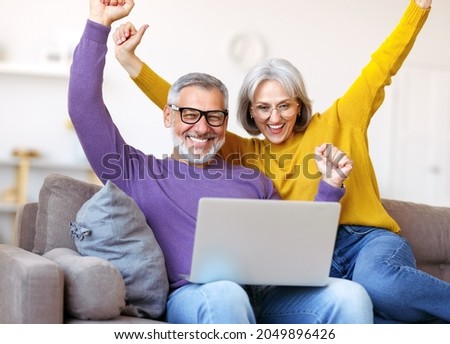 Overjoyed excited senior family couple celebrating success while sitting on sofa with laptop, happy retired man and woman receiving email with positive good news, seniors winning lottery Royalty-Free Stock Photo #2049896426