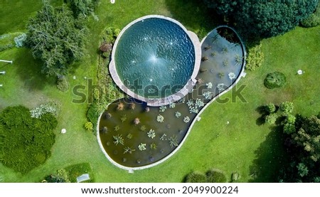 A nice and peaceful garden pond with water lilies and working fountain - fresh green plants in spring time, and decorative 
turquoise water