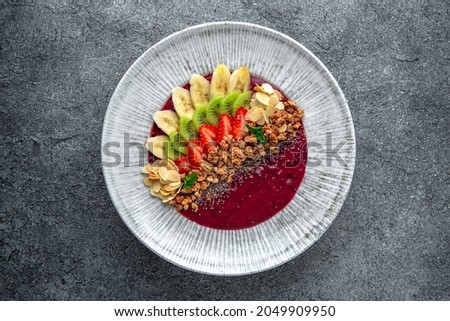 Healthy vegetarian wholesome breakfast chia seed porridge with berries, fruits and nuts and strawberry puree. Ready menu for the restaurant. Neutral gray blue textured background