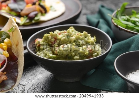 Bowl with tasty guacamole on dark background, closeup