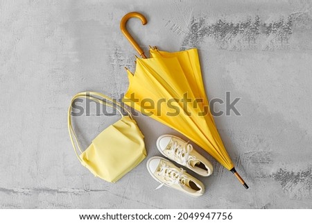 Stylish umbrella, sneakers and bag on light background