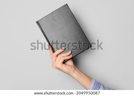 Woman holding book on grey background