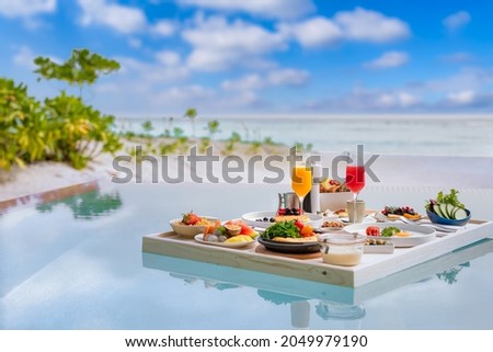 Breakfast in swimming pool, floating breakfast in luxurious tropical resort. Table relaxing on calm pool water, healthy breakfast and fruit plate by resort pool. Tropical couple beach luxury lifestyle Royalty-Free Stock Photo #2049979190