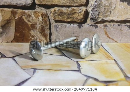 Photo of three roof studs on the floor against a stone wall