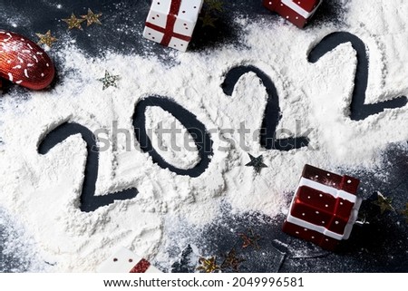 Happy New year 2022 celebration. Christmas toys and written 2021 on black background. Flat lay.