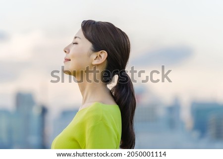 Young asian woman closing eyes in front of the city. Royalty-Free Stock Photo #2050001114