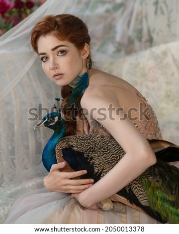 Red-haired girl with a thick braid and a blue peacock in her hands