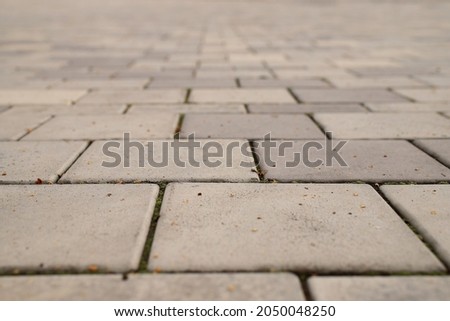 a view from below of a street covered with stone paving stones with a blurred background