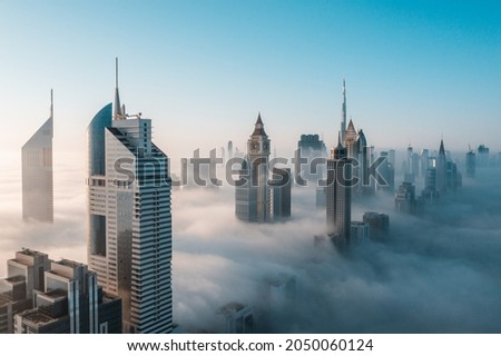 Mega tall skyscrapers of Dubai covered in early morning think fog. Rare aerial perspective.  Royalty-Free Stock Photo #2050060124