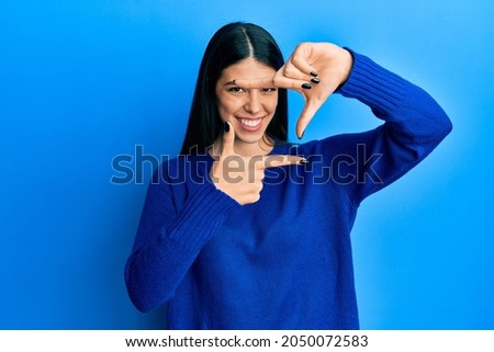Young hispanic woman wearing casual clothes smiling making frame with hands and fingers with happy face. creativity and photography concept. 
