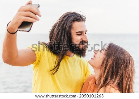 Happy couple on vacation take a funny selfie with smart phone - lifestyle and sharing concept
