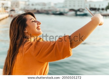 Young woman on vacation takes a selfie by the sea - lifestyle, tourism and sharing moments concept
