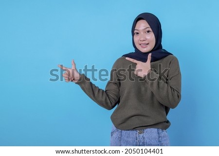 Smiling happy asian woman with her finger pointing isolated on light blue banner background