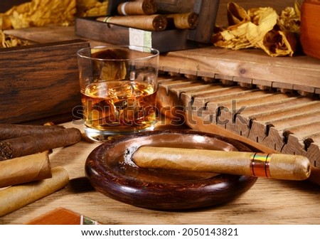 Cigars with Whisky and Tobacco Leaves on wooden Background. Cigar in an Ashtray. Royalty-Free Stock Photo #2050143821