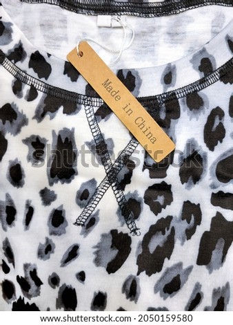 Close up of brown Made In China tag on gray and black leopard shirt pattern