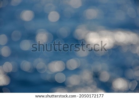 Bokeh background of blue sea water with sun reflections.