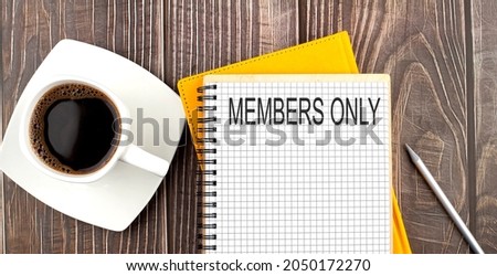MEMBERS ONLY text on the notebook with coffee on the wooden background