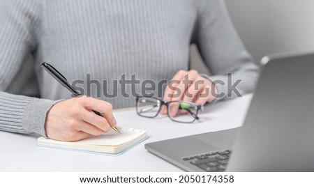 Closeup photo of woman working with laptop and writing in notebook 