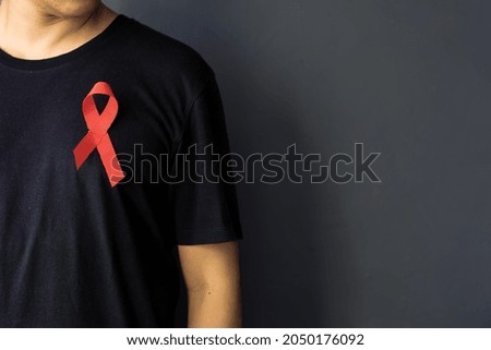 World Aids Day and World Diabetes Day with man wearing red AIDS awareness ribbon on chest. Healthcare and medicine concept.  Royalty-Free Stock Photo #2050176092